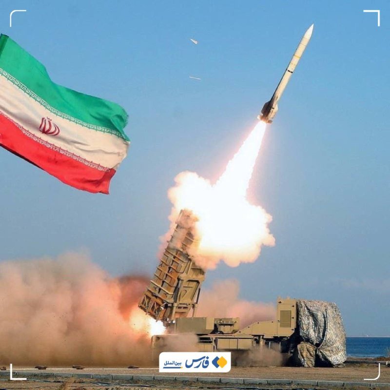 A missile launches skyward from a mobile launcher, with an Iranian flag waving in the foreground and a logo visible at the bottom.