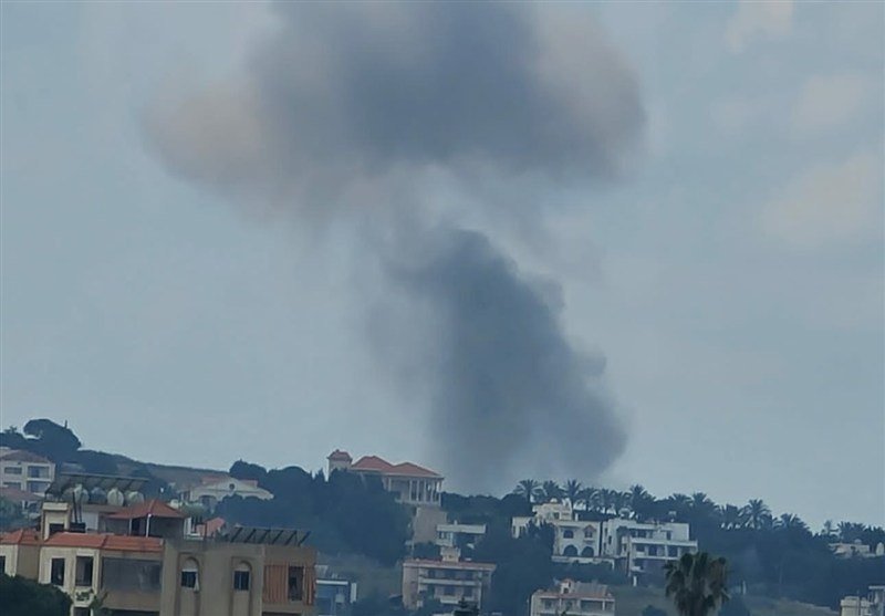 A large plume of dark smoke rises above a hillside neighborhood of white buildings with red-tiled roofs.