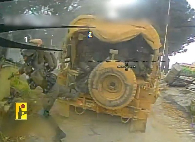 Armored soldiers in tactical gear stand beside a tan military vehicle with a mounted spare tire in a dusty outdoor setting, captured from a helmet-cam perspective.