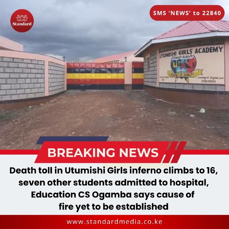 A closed gate with black, yellow, and red stripes stands before a building labeled "Utumishi Girls Academy" under a cloudy sky.