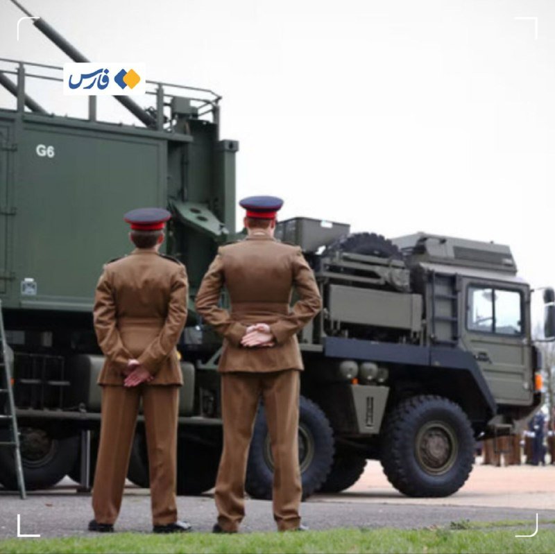 Two uniformed personnel stand at attention with hands clasped behind their backs, facing a large green military vehicle marked "G6" equipped with a mounted cannon.