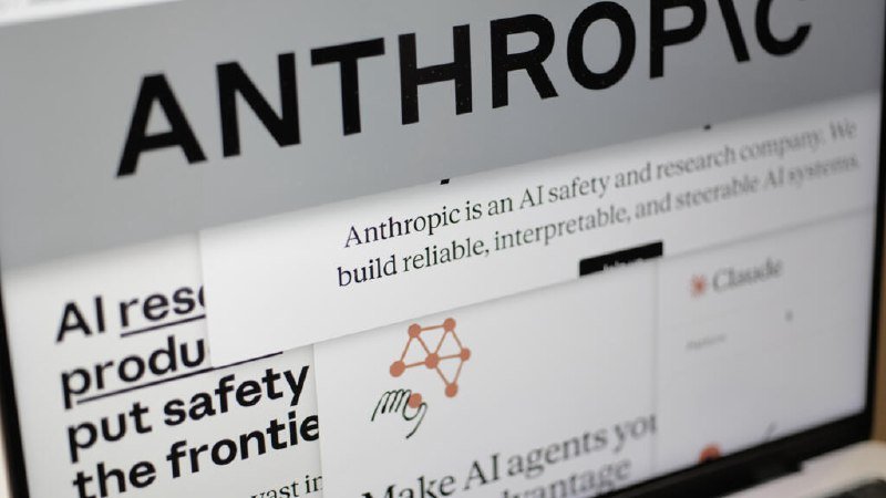 Close-up of layered print materials displaying the "ANTHROPIC" wordmark alongside text describing the company as an "AI safety and research company."