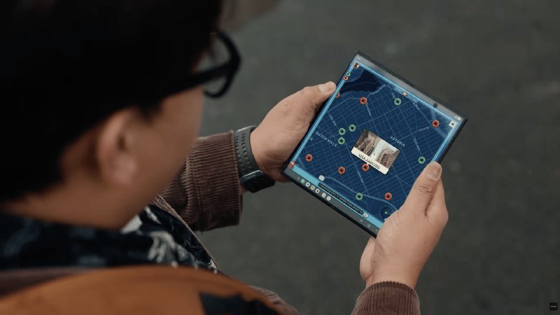A person wearing glasses holds a foldable smartphone displaying a dark city map with pinned locations and an embedded photo.