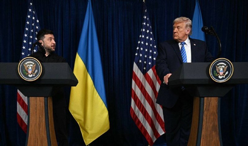 Two men in dark suits stand at separate podiums bearing presidential seals, with Ukrainian and American flags displayed behind them.