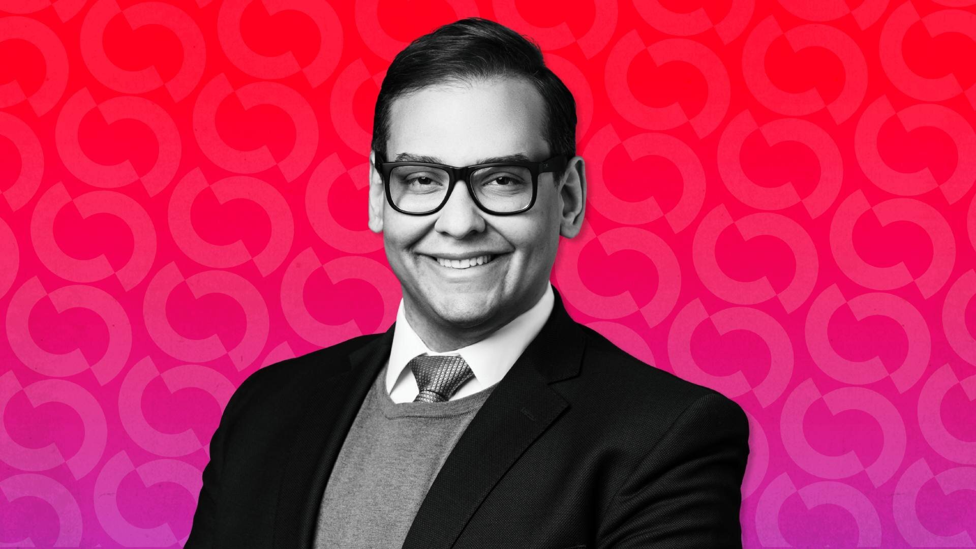 A smiling man in a dark blazer, sweater, tie, and black-rimmed glasses poses against a red-and-pink patterned background.
