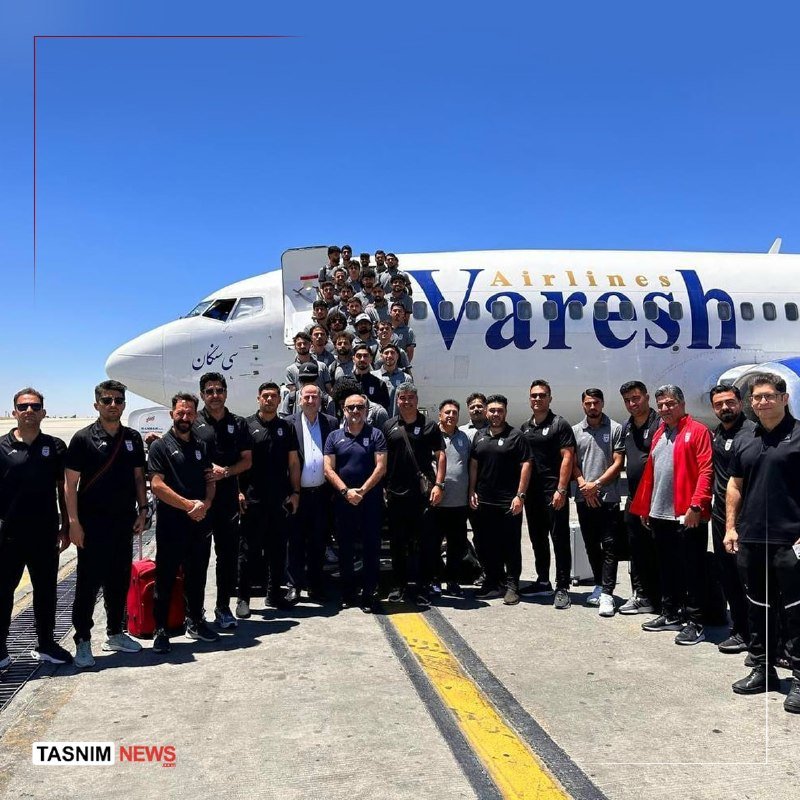 A large group of people poses in front of a "Varesh Airlines" aircraft on a sunny tarmac, with some standing on the boarding stairs.