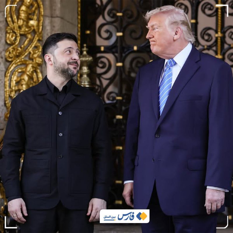 Two men stand facing each other before ornate golden gates, one in a black collared jacket and the other in a navy suit with a striped tie.