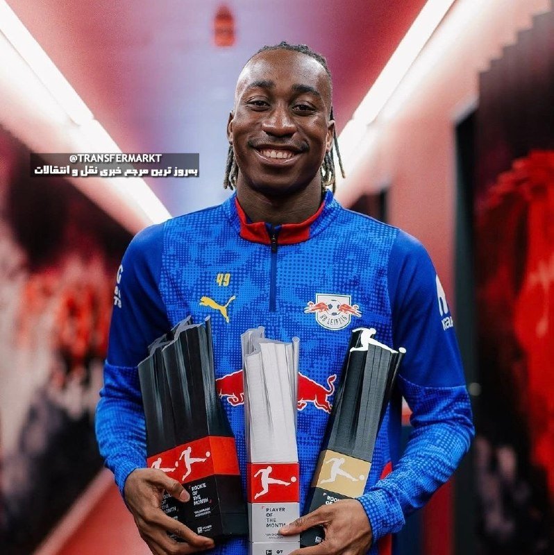 A smiling man in a blue RB Leipzig tracksuit holds three Bundesliga "Rookie of the Month" trophies, with a "@TRANSFERMARKT" watermark visible.