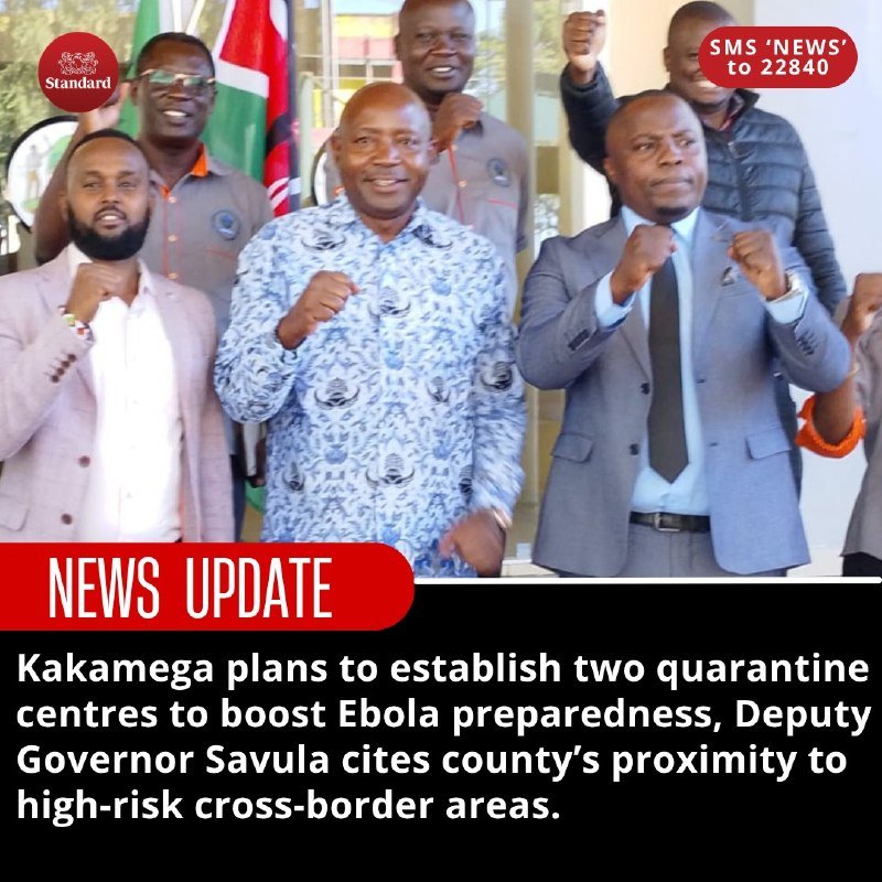 A group of men in formal and patterned attire pose with raised fists and smiles indoors, with a Kenyan flag and a "Standard" logo visible in the background.