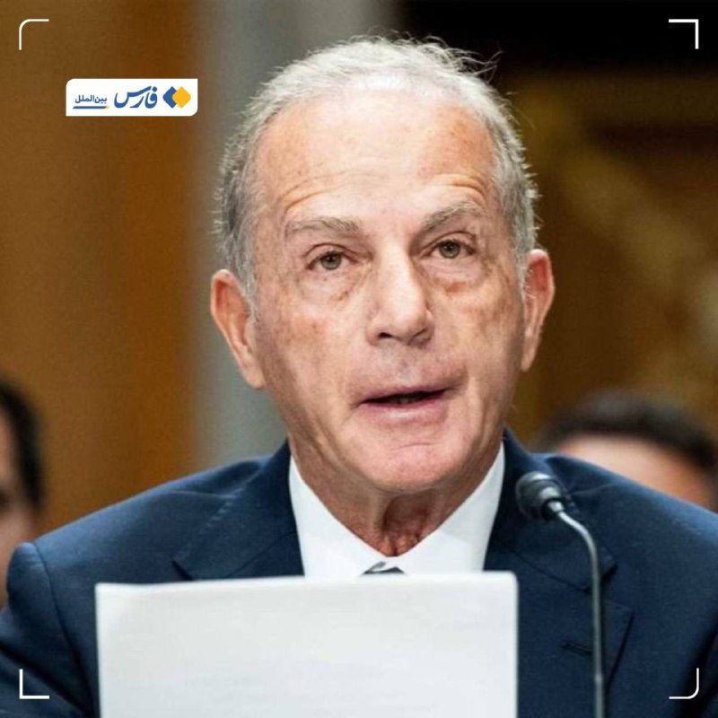 An older man with gray hair, wearing a dark suit and tie, speaks into a microphone while seated at a desk with papers, in a formal hearing setting.
