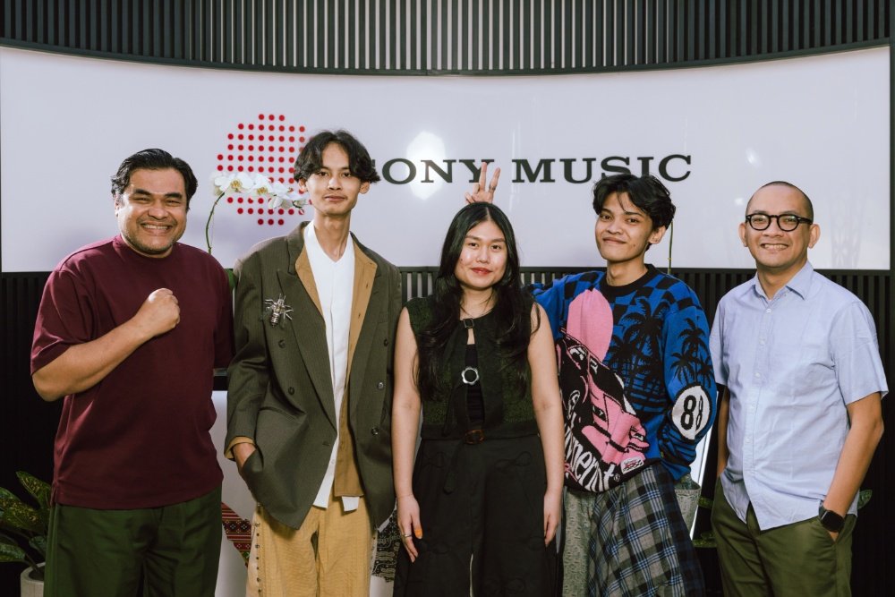 Five people pose together smiling in front of a white backdrop displaying a "SONY MUSIC" logo and red dotted graphic.
