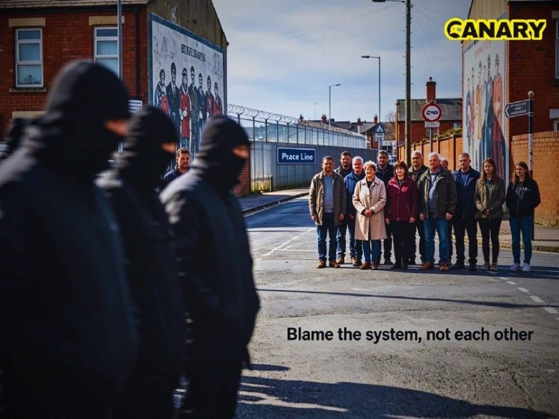 A group of masked figures stands in the foreground facing a line of civilians across a street, with a "CANARY" logo in the corner and the text "Blame the system, not each other" overlaid.
