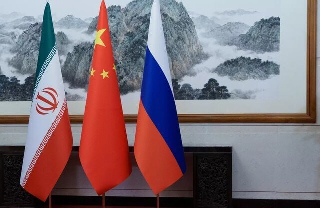 Three flags—Iran, China, and Russia—stand in front of a framed landscape painting.