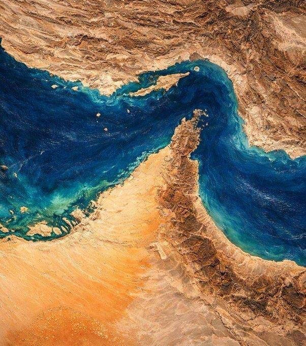 Satellite image showing a narrow blue waterway winding between arid, brown and tan desert landmasses.