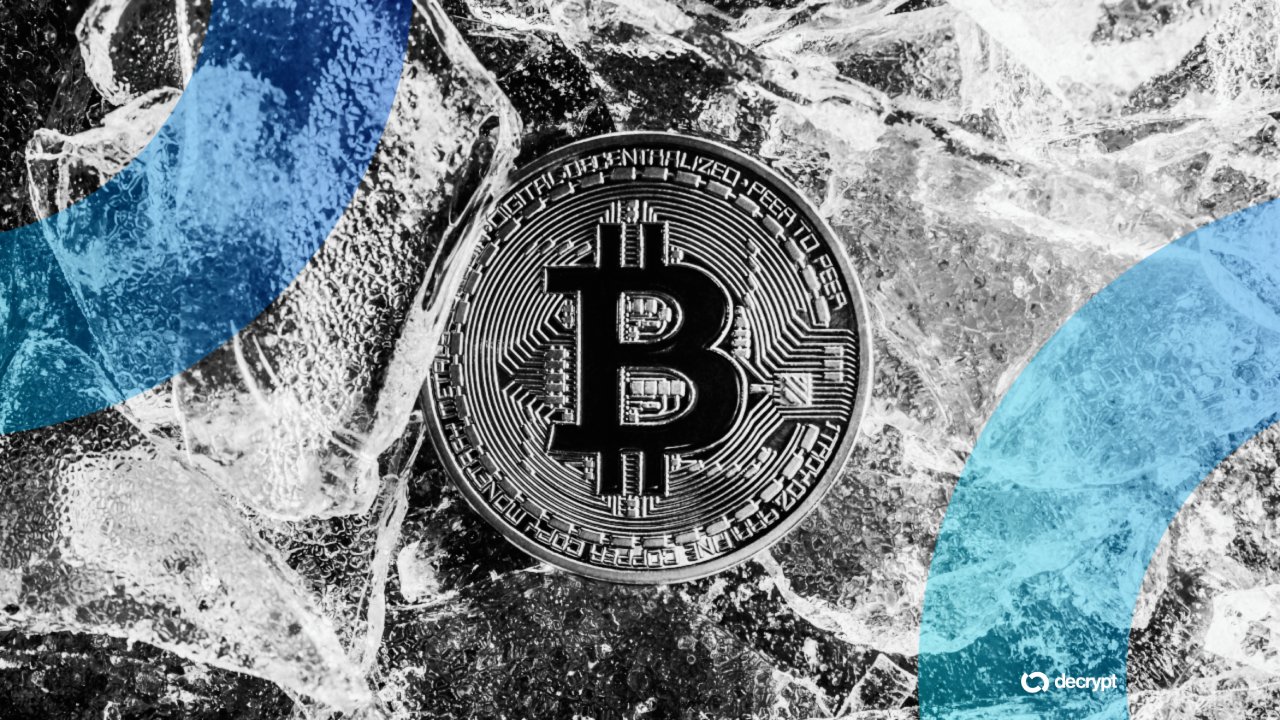 A physical Bitcoin token with a circuit-board design rests on crumpled plastic sheeting, overlaid with blue and teal graphic banners and a "decrypt" logo.