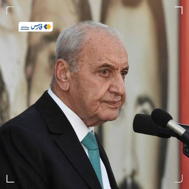 An elderly man in a dark suit and green tie speaks into microphones, with a Persian news channel logo visible in the corner.