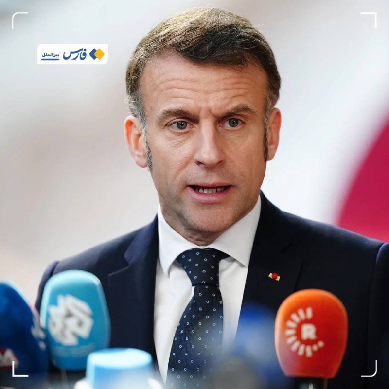 A man in a dark suit and patterned tie speaks at a press conference, surrounded by multiple microphones in the foreground.