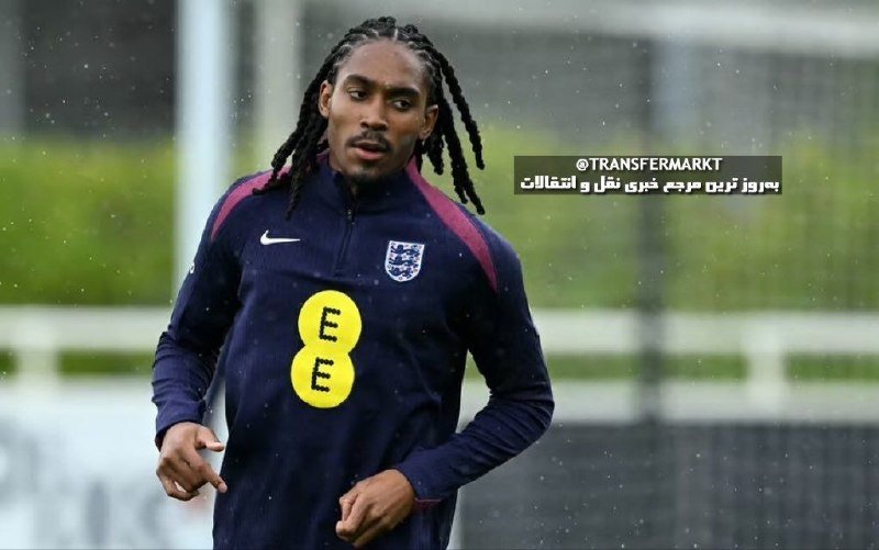 A football player with long dreadlocks jogs on a training pitch while wearing a dark navy England training top featuring the Three Lions crest and a yellow EE sponsor logo.