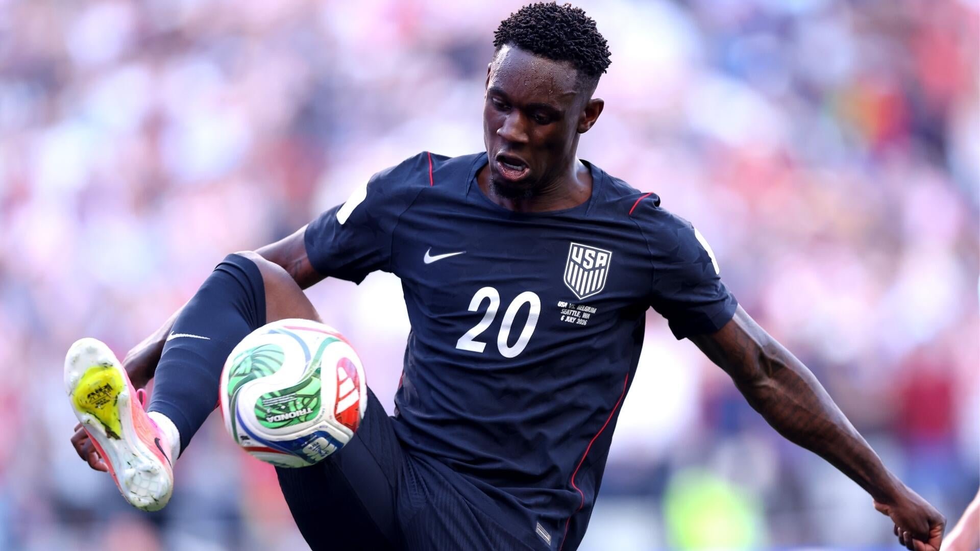 A USA soccer player wearing jersey number 20 controls a ball mid-air with his foot during a match.