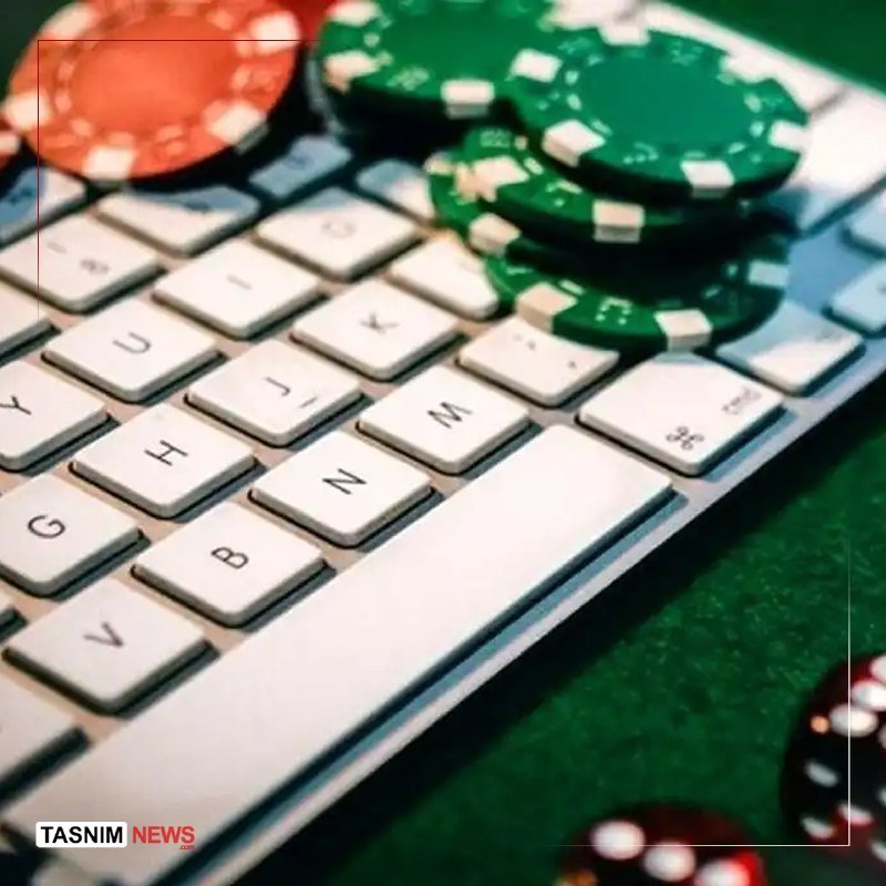 A stack of green poker chips and scattered red chips rest on a white computer keyboard atop a green felt surface.