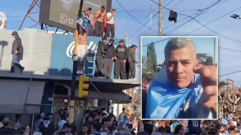 A crowd gathers below a billboard where people stand, one waving a light blue and white flag, alongside an inset photo of a man wearing a light blue and white scarf.