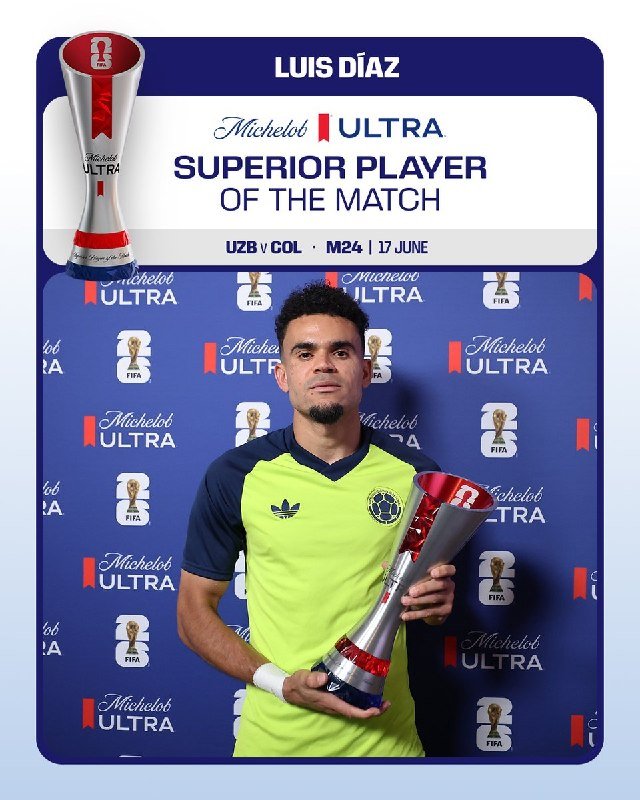 A soccer player in a yellow and navy jersey holds a silver trophy in front of a blue "Michelob Ultra Superior Player of the Match" backdrop featuring FIFA and World Cup logos.
