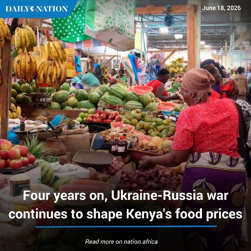 A bustling market stall displays bananas, watermelons, apples, pineapples, and other produce, with a woman in a red top shopping under a green polka-dot umbrella.