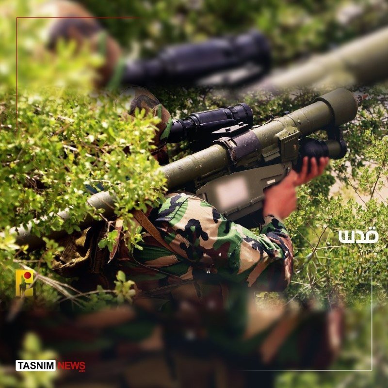 Soldiers in camouflage uniforms aim a shoulder-fired weapon system while lying concealed in green foliage, with a "Tasnim News" logo visible.
