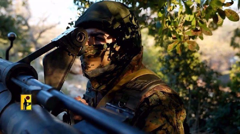 A masked person in camouflage clothing aims a large firearm amid green foliage.