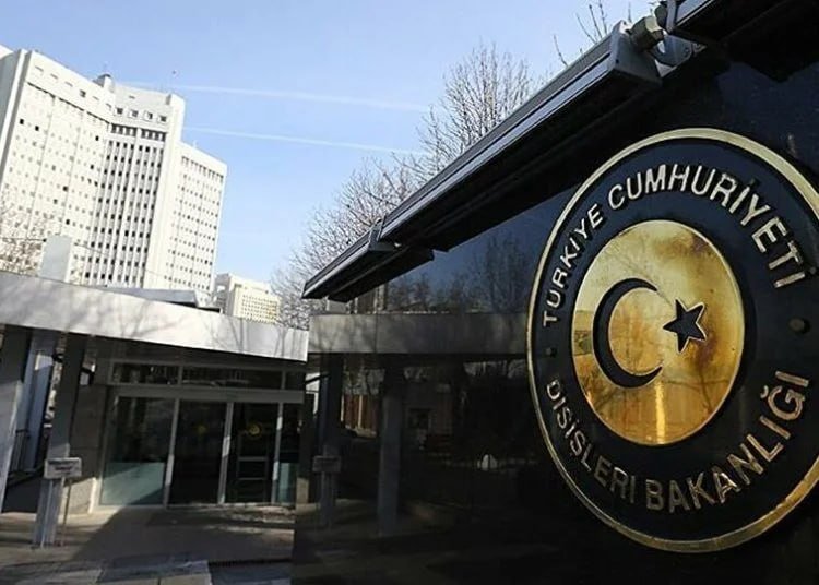 A government building entrance displays a gold and black emblem reading "TÜRKİYE CUMHURİYETİ DIŞİŞLERİ BAKANLIĞI" with a crescent and star.