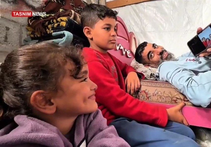 A "Tasnim News" watermark appears on an image of two children and a bearded man reclining together on patterned cushions against a plastic-covered wall.