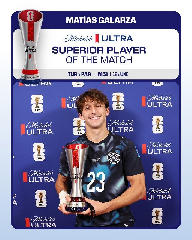 A smiling soccer player in a dark jersey numbered 23 holds a Michelob ULTRA Superior Player trophy in front of a branded backdrop.