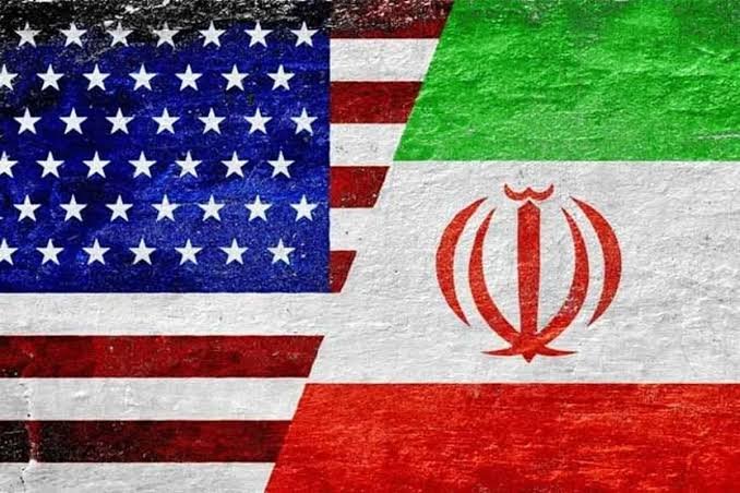 The flags of the United States and Iran are painted side by side on a textured wall, divided diagonally.