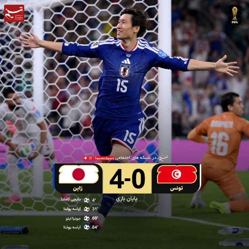 A Japanese soccer player in a blue jersey with number 15 celebrates with outstretched arms in front of a goal net, while an orange-clad Tunisian player kneels in the background.