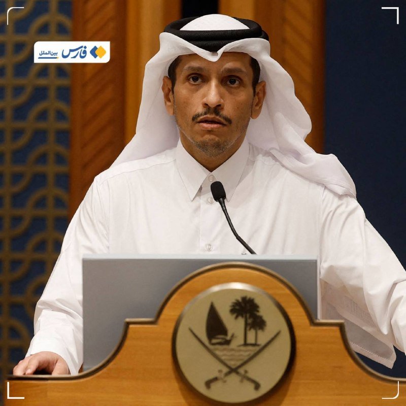 A man in traditional Arab dress speaks at a podium displaying an emblem with palm trees and a dhow, with Arabic text visible in the corner.