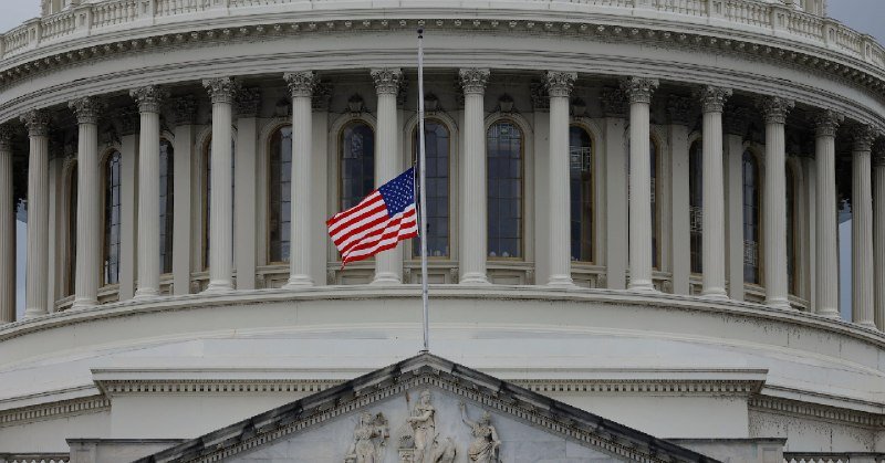An American flag flies at half-staff above the columned dome of the U.S. Capitol building.