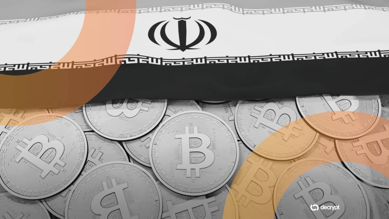An Iranian flag rests above a pile of silver Bitcoin tokens, with a "decrypt" logo in the corner.