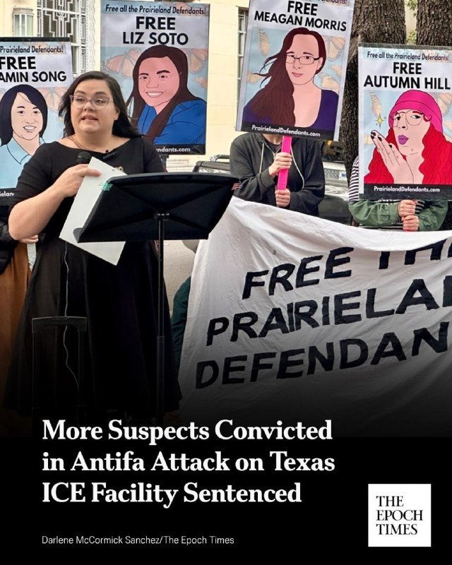 A woman speaks at a podium outdoors while holding a "Free Autumn Hill" sign, beside others displaying illustrated portraits and a "Prairieland Defendants" banner.