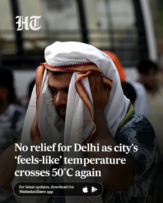 A man wearing a white cloth draped over his head and a patterned garment stands among a crowd, holding the cloth to his face.