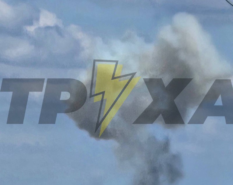 The ТРИХА logo in black and yellow lettering is overlaid on a background image of dark smoke rising into a cloudy sky.