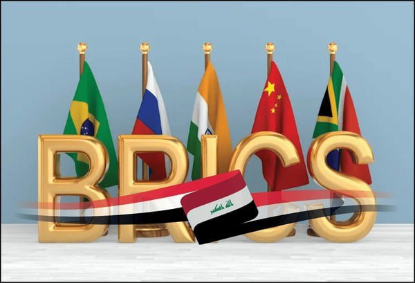 A 3D graphic displays golden "BRICS" letters in front of the flags of Brazil, Russia, India, China, and South Africa, with an Iraqi flag placed before the text on a white surface.