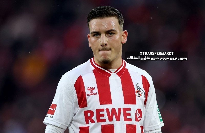 A soccer player wearing a red and white striped Hummel jersey with "REWE" sponsorship looks forward on the field during a match.