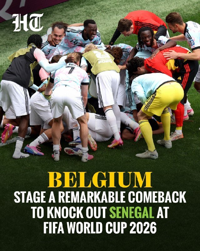 A football team in light blue jerseys celebrates in a jubilant pile-up on the pitch, with graphic text reading "Belgium stage a remarkable comeback to knock out Senegal at FIFA World Cup 2026."