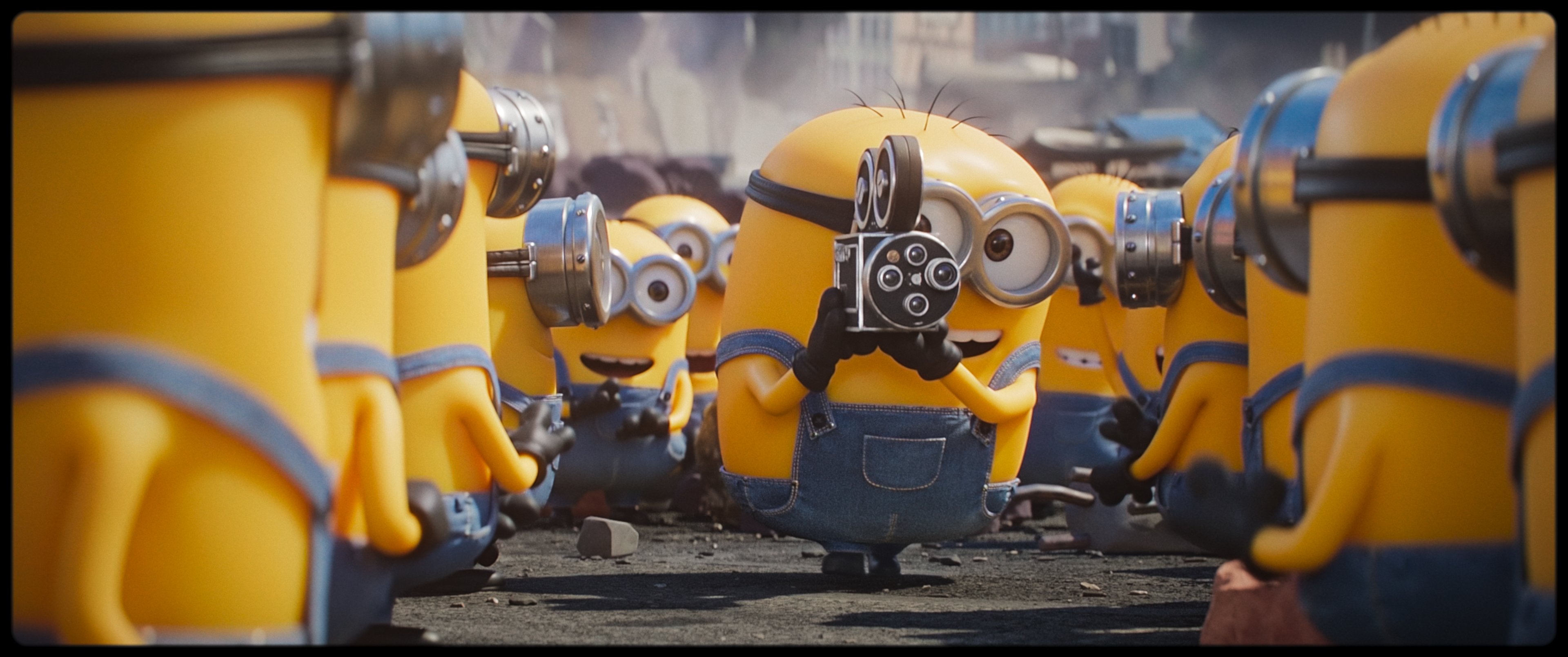 A central Minion character holds a vintage film camera while surrounded by other Minions wearing goggles and denim overalls in an animated CGI scene.