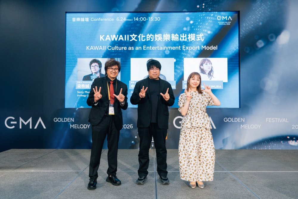 Three people pose with peace signs in front of a conference screen reading "KAWAII Culture as an Entertainment Export Model" at a Golden Melody Festival event.