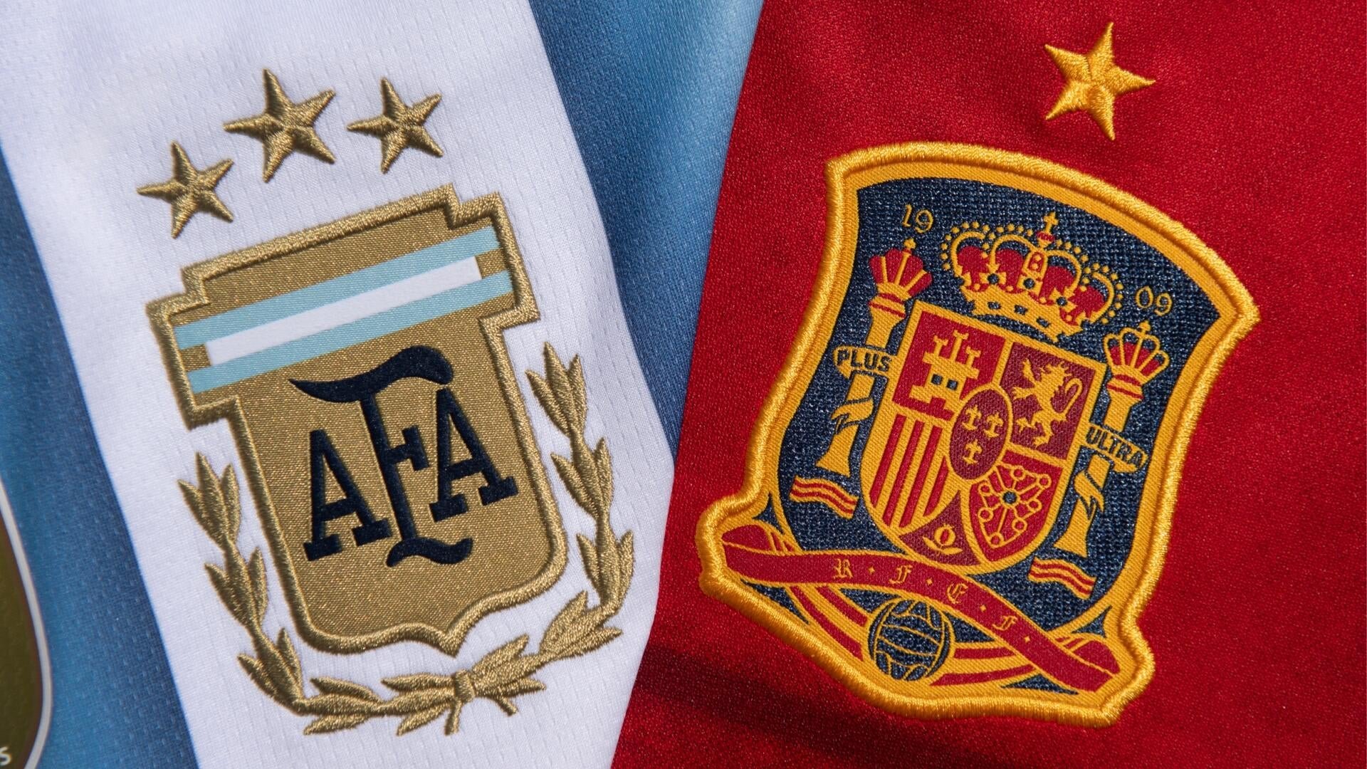Two embroidered national football team crests are displayed side by side: the Argentina AFA badge with three stars on light blue and white stripes, and the Spain RFEF shield on a red background.