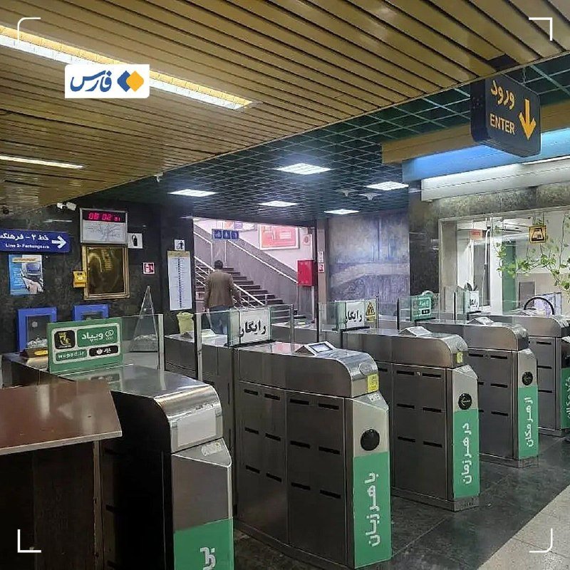 Row of metallic subway turnstiles with green panels stands inside a tiled station, with a person walking toward a staircase beneath an illuminated "ENTER" sign.