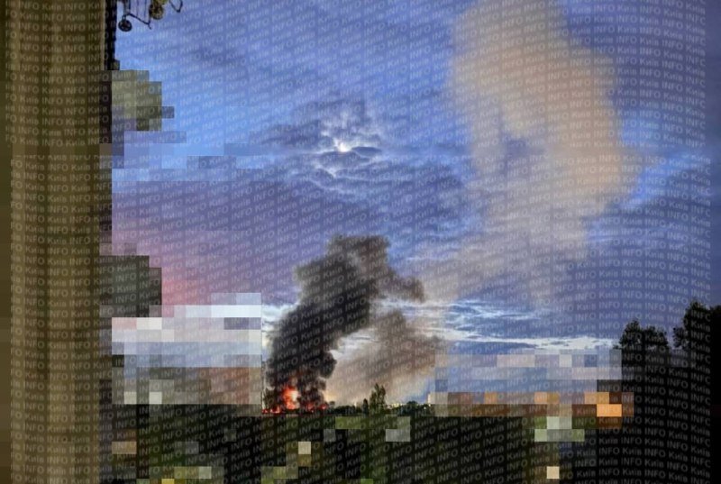 A photo shows a fire with rising smoke in a rural field at dusk under a cloudy sky, overlaid with repeating "INFO KIEV" watermark text.