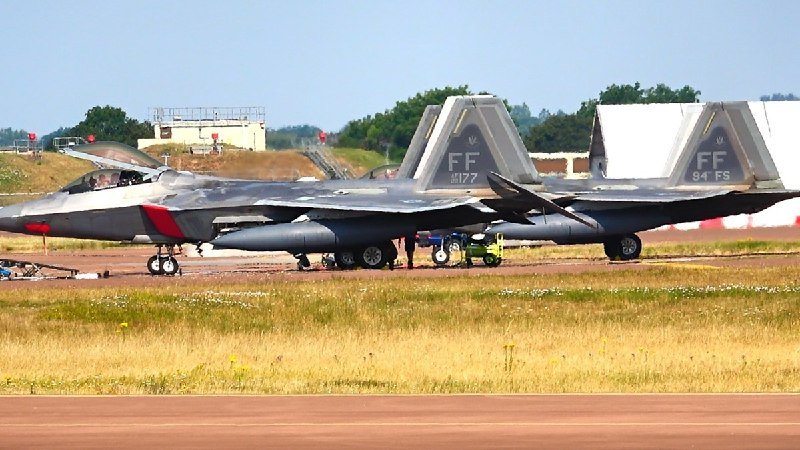 Two gray fighter jets with "FF" tail markings and "177" and "84 FS" numbers sit on a tarmac alongside a grass field.