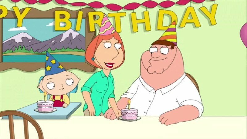 Animated scene showing a cartoon family wearing party hats at a table with two lit birthday cakes beneath a "HAPPY BIRTHDAY" banner.